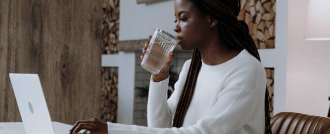 woman working at desk drinking fresh water