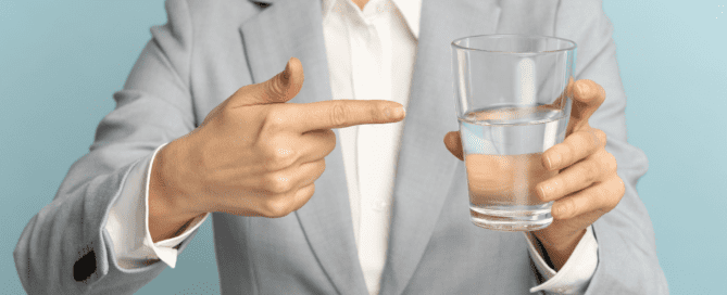 woman holding and pointing to a glass of water